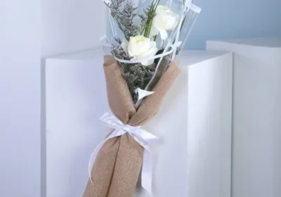 A bouquet featuring three stems of Sovereign Roses with Caspia leaves, showcasing elegant double white blooms.