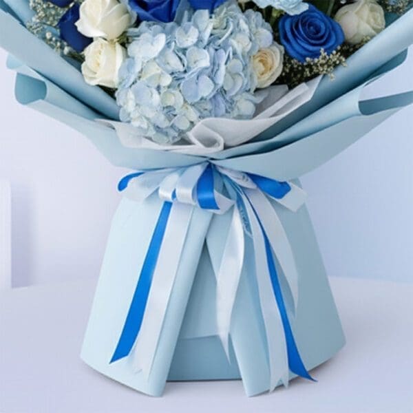 Blue baby boy bouquet with roses, hydrangeas, and other blooms and “It’s a Boy” card.