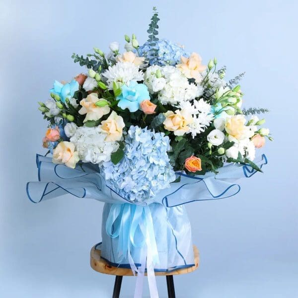 blue-hydrangea-bouquet Bouquet featuring hand-tied blue hydrangeas, cream roses, lisianthus & chrysanthemums in blue wrap, finished with layered ribbons.