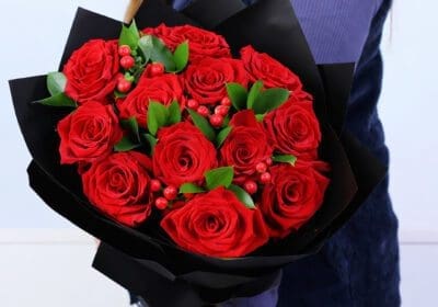 12 red roses with hypericum berries and ruscus greens bouquet in elegant black wrapping