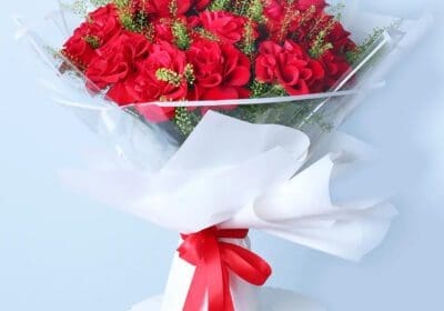 Red roses in white wrap with a ribbon.