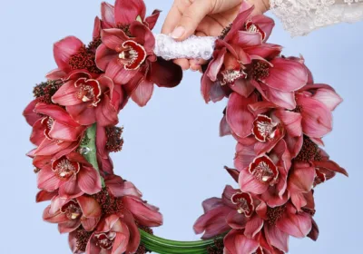Modern Cymbidium Bridal Bouquet featuring red cymbidium orchids, skimmia berries, and sculptural steel grass in a contemporary bridal arrangement