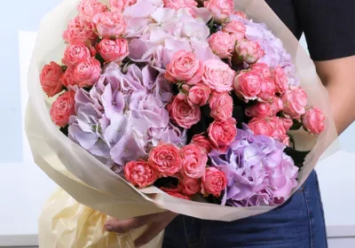 Pastel Symphony Bouquet featuring orange spray roses and purple hydrangea arranged in a vibrant and elegant floral design