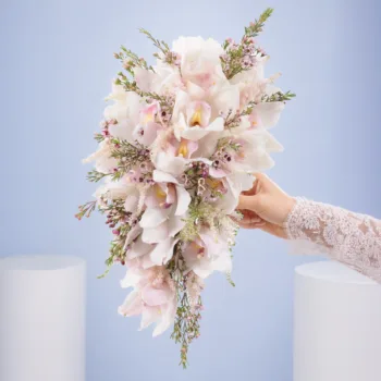 Romantic White Wedding Bouquet featuring white cymbidium orchids, pink wax flowers, and astilbe in a luxurious waterfall bridal arrangement