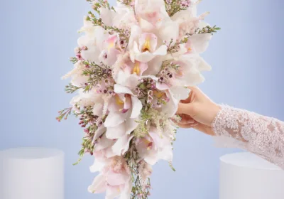 Romantic White Wedding Bouquet featuring white cymbidium orchids, pink wax flowers, and astilbe in a luxurious waterfall bridal arrangement