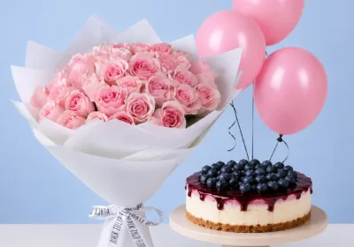 Pink Bouquet & Blueberry Cheesecake Combo featuring light pink Titanic roses, a 1 kg blueberry cheesecake, and light pink balloons for birthdays and special celebrations.