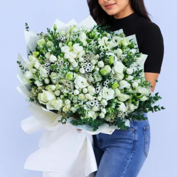 Pure White Elegance Bouquet featuring white roses, spray roses, lisianthus, wax flowers, santini, alstroemeria, and parvifolia arranged as a luxurious fresh floral bouquet.