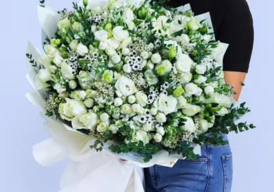 Pure White Elegance Bouquet featuring white roses, spray roses, lisianthus, wax flowers, santini, alstroemeria, and parvifolia arranged as a luxurious fresh floral bouquet.
