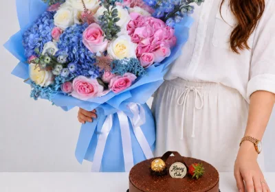 Blue Bliss Bouquet & Ferrero Rocher Cake featuring blue and pink hydrangeas, light pink and cream roses, blue delphiniums, astilbe, and a rich chocolate Ferrero Rocher cake.