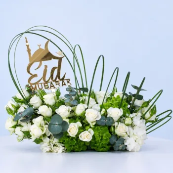 Eid Harmony Floral Arrangement featuring white roses, white and green hydrangeas, eucalyptus, and arched steel grass with an Eid topper for festive décor