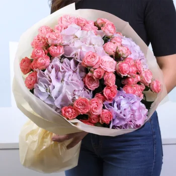 Pastel Symphony Bouquet featuring orange spray roses and purple hydrangea arranged in a vibrant and elegant floral design